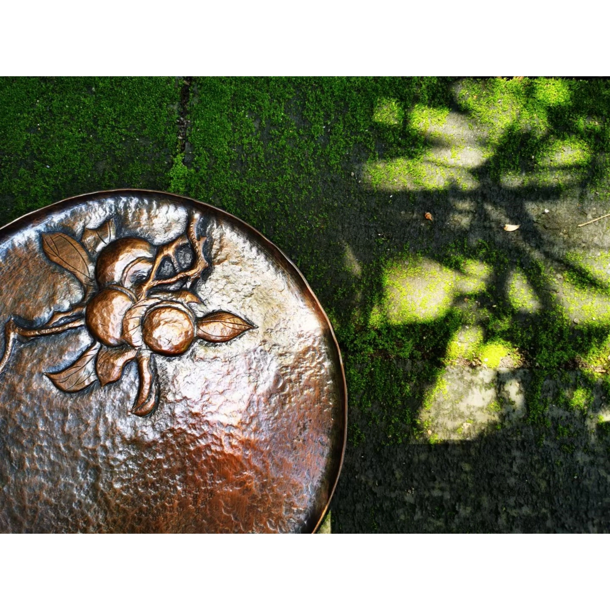 Detail of copper teacup saucer engraved motif and oxidized patina, highlighting the contrast between carving and hammered finish,