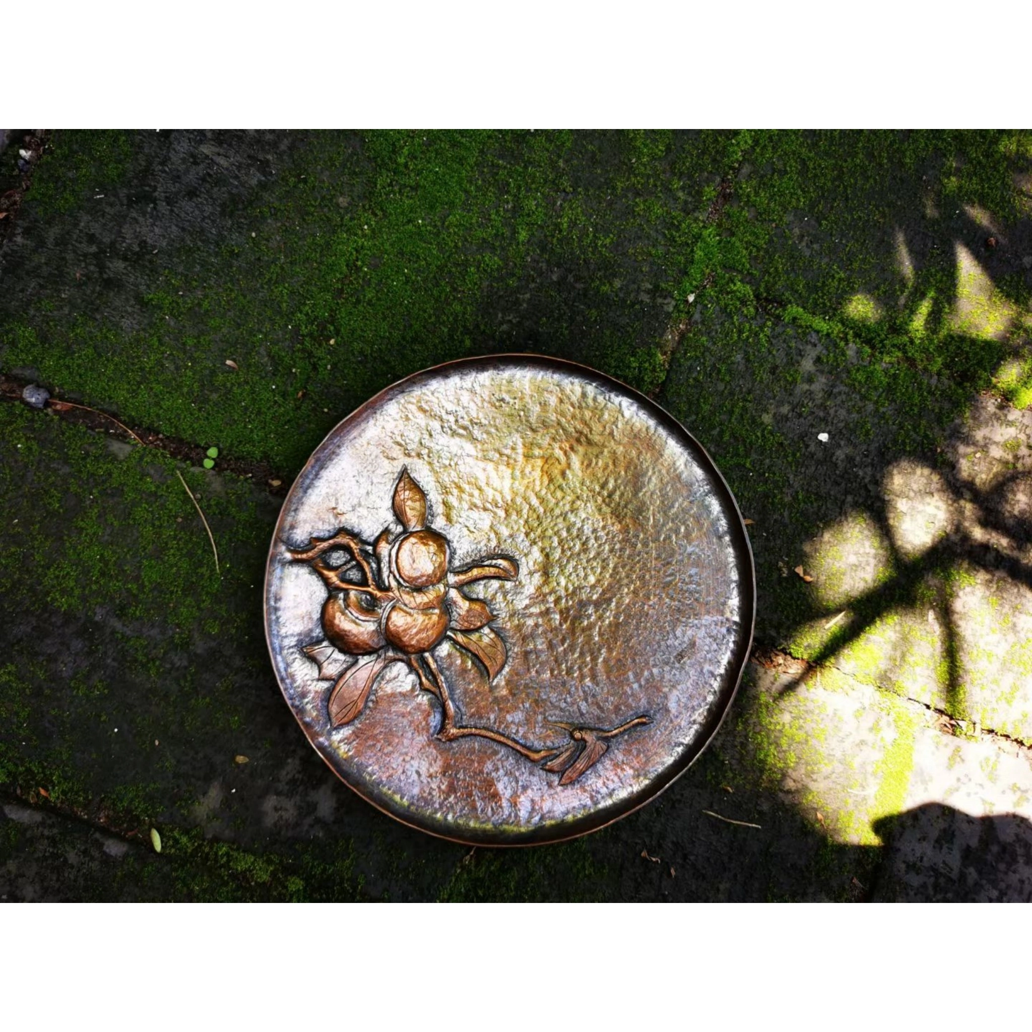 Full view of hand-hammered copper teacup saucer featuring engraved decorative motif and brushed texture,