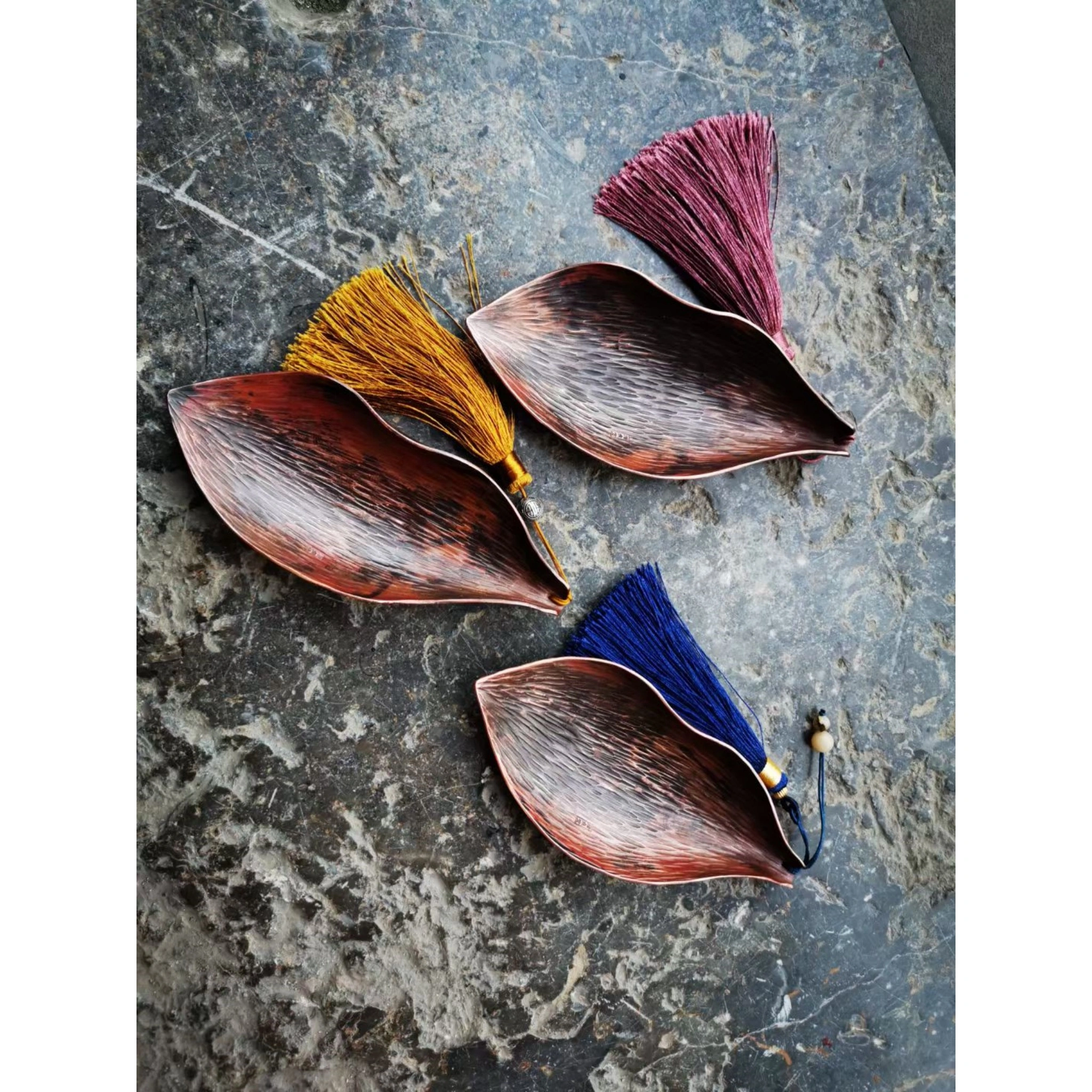 Set of three hammered copper leaf-shaped tea scoops, showing different leaf vein patterns and oxidized copper tones,