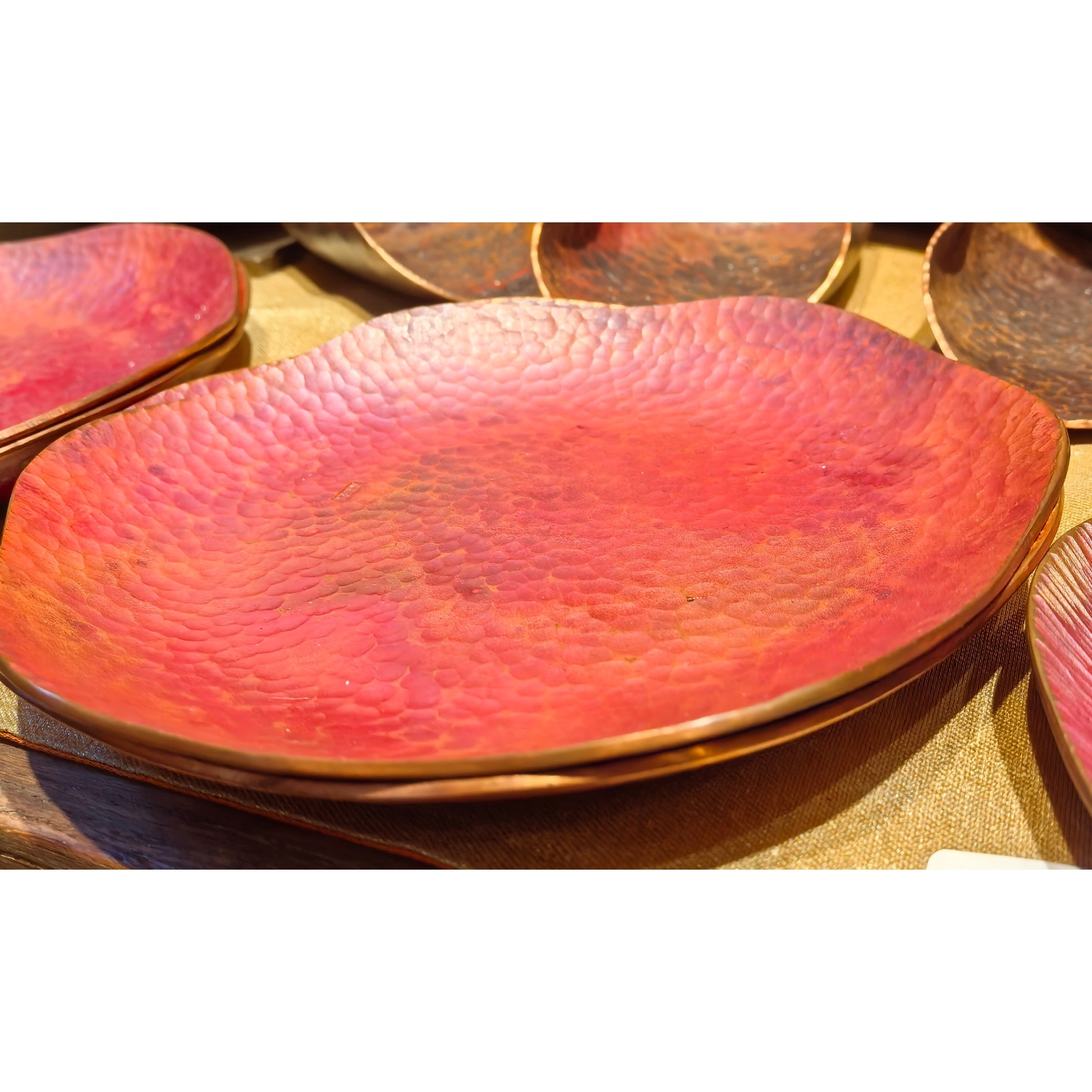 Side profile of a hand-hammered copper teapot stand, emphasizing the patina depth and sculptural quality from an angle