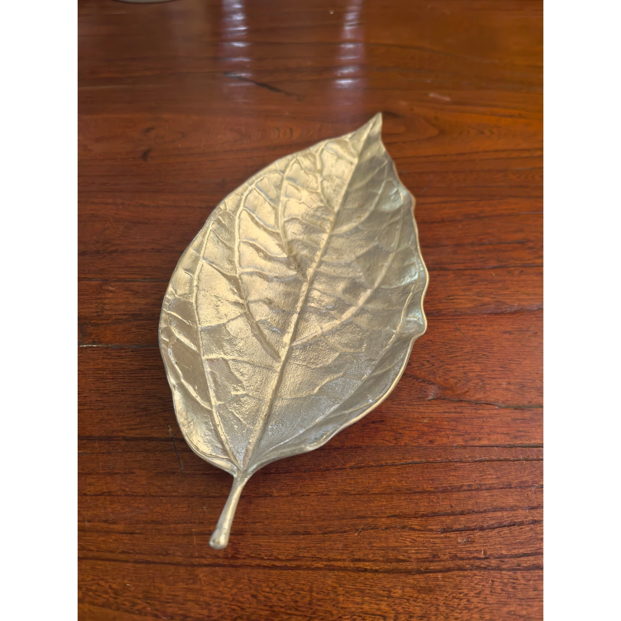 Hammered tin leaf-shaped tea scoop front view, showing leaf vein contour and hammered texture,