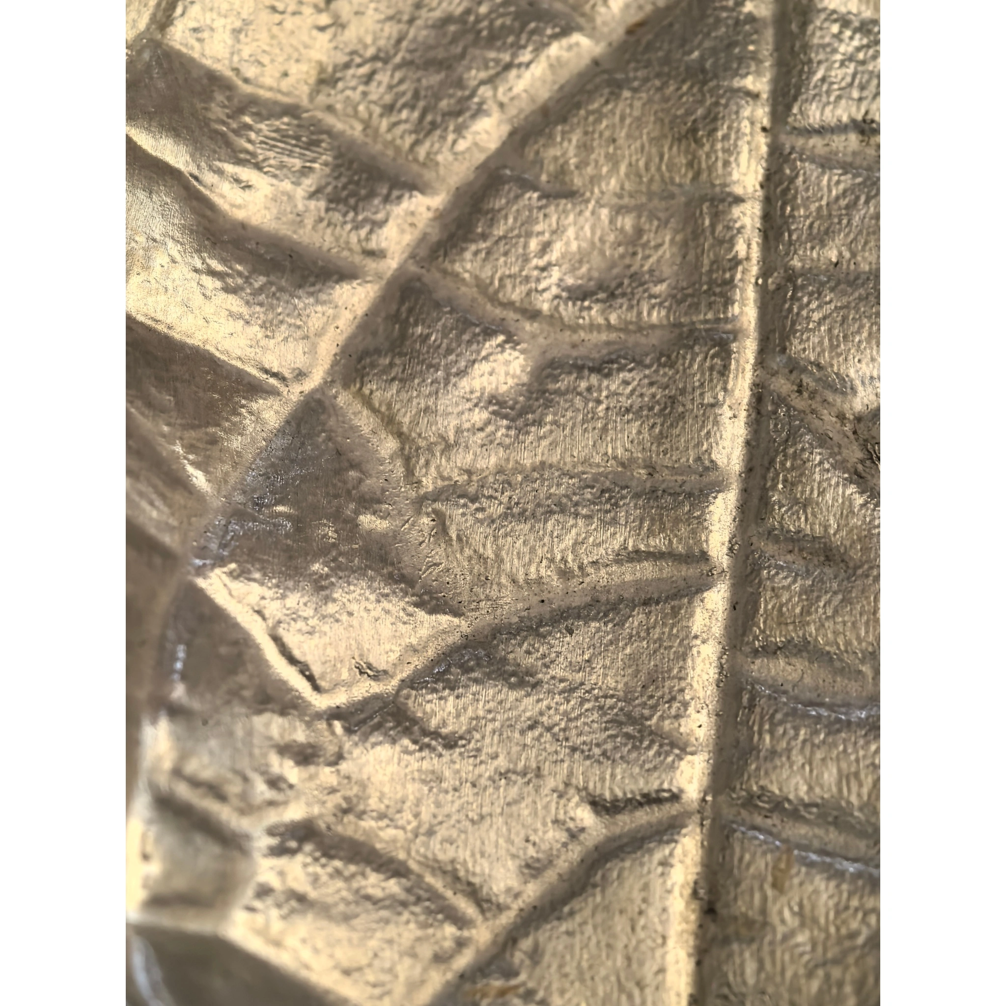 Close-up of hammered texture on leaf-shaped tin tea scoop, showing detailed dimpled surface and handcrafted finish