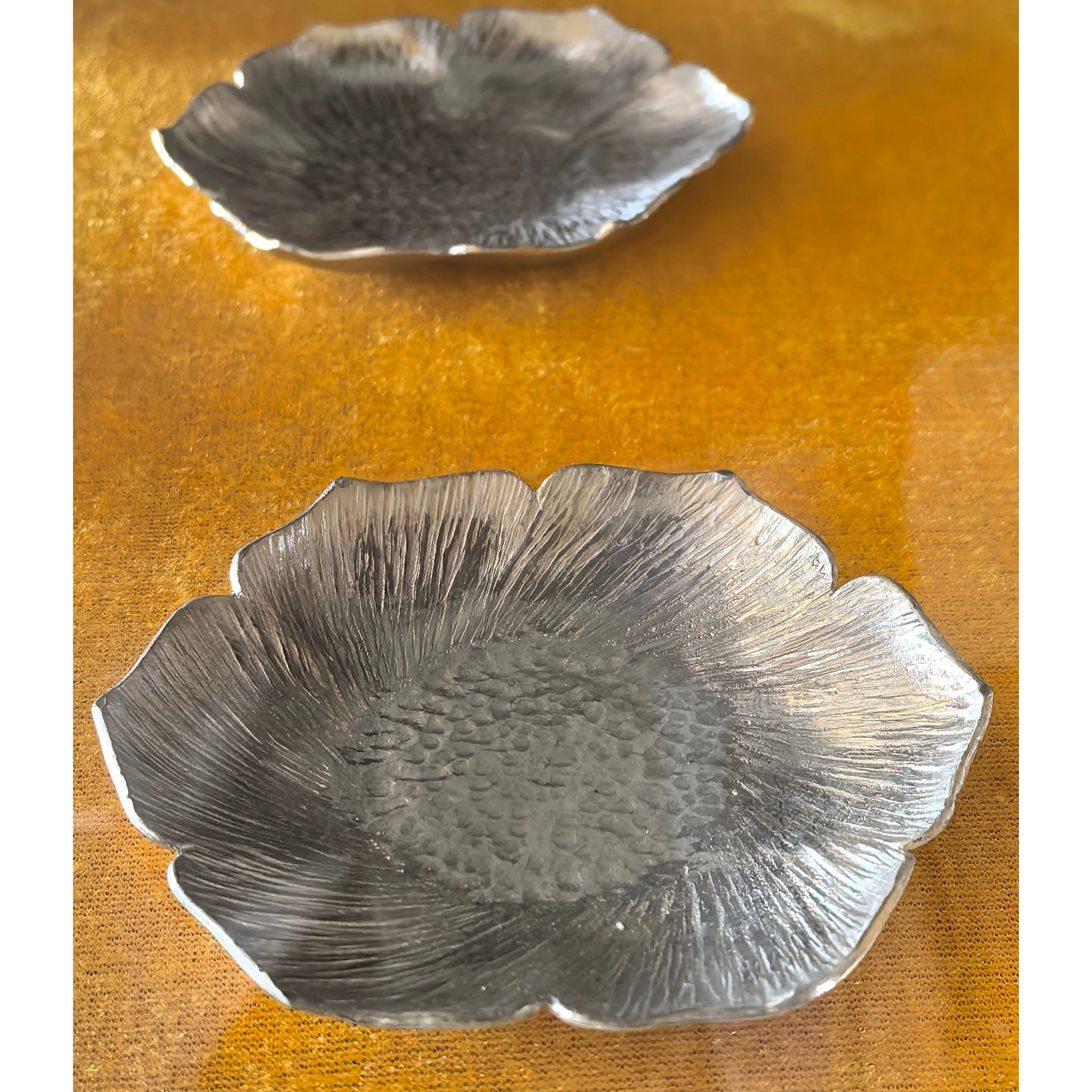 Hammered tin petal-shaped teapot stand from another angle, showing curved petal contour and hammered texture,