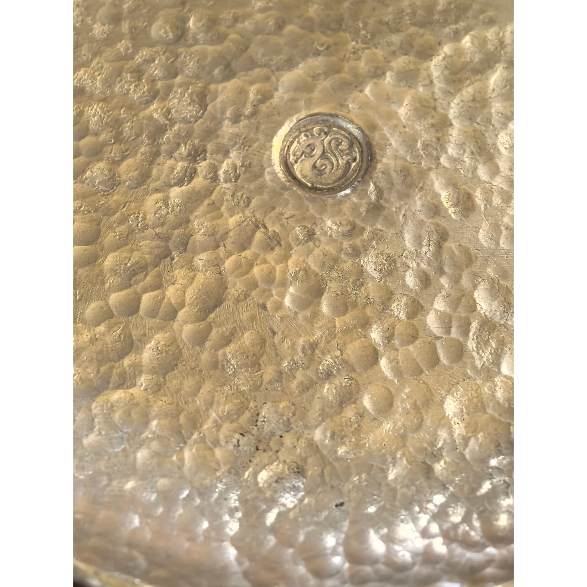 Close-up of hammered texture on tin teacup saucer, showing detailed dimpled surface and handcrafted finish,