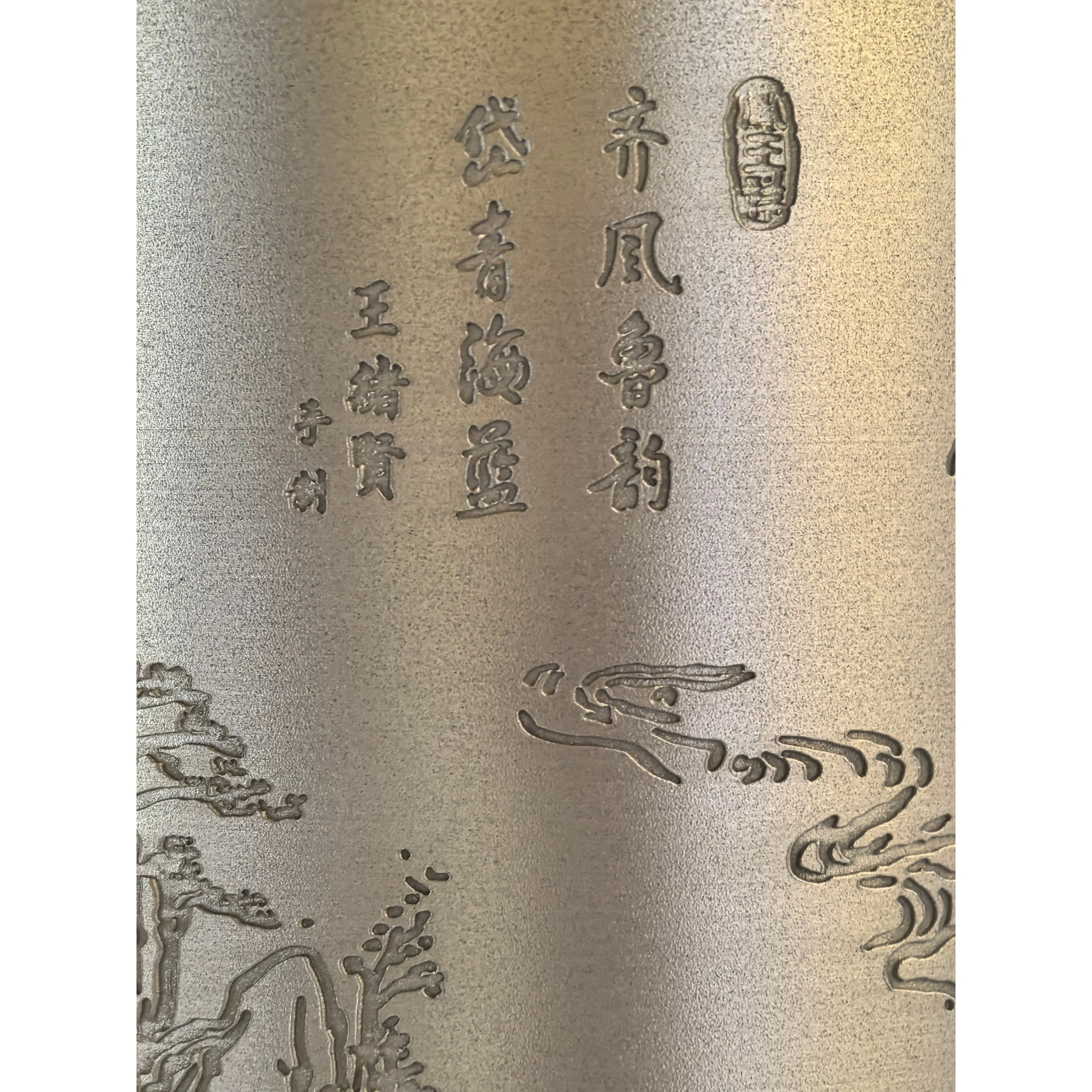 Close-up of hand-engraved calligraphy on tin tea caddy, showing carved text and artistic lettering,
