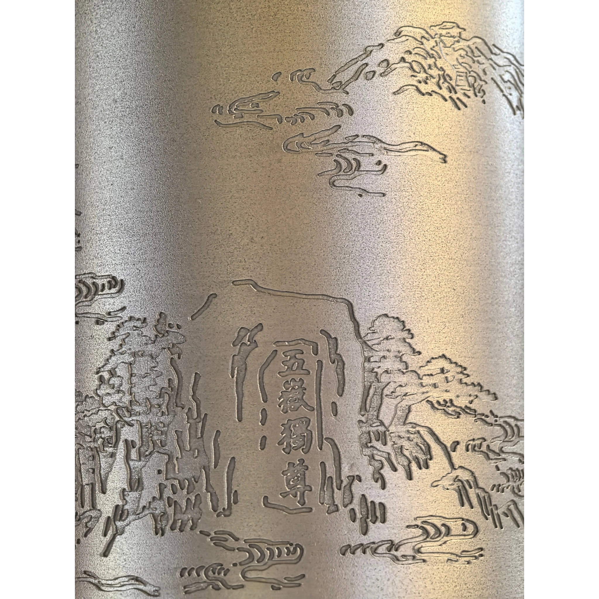 Close-up of hand-engraved Mount Tai landscape on tin tea caddy, showing mountain scenery and carved rock textures,