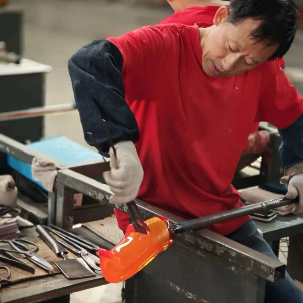 Skilled glassmaker shaping imperial yellow glass vase with hand tools, traditional Chinese glassmaking craft, by Heritage & Craft.
