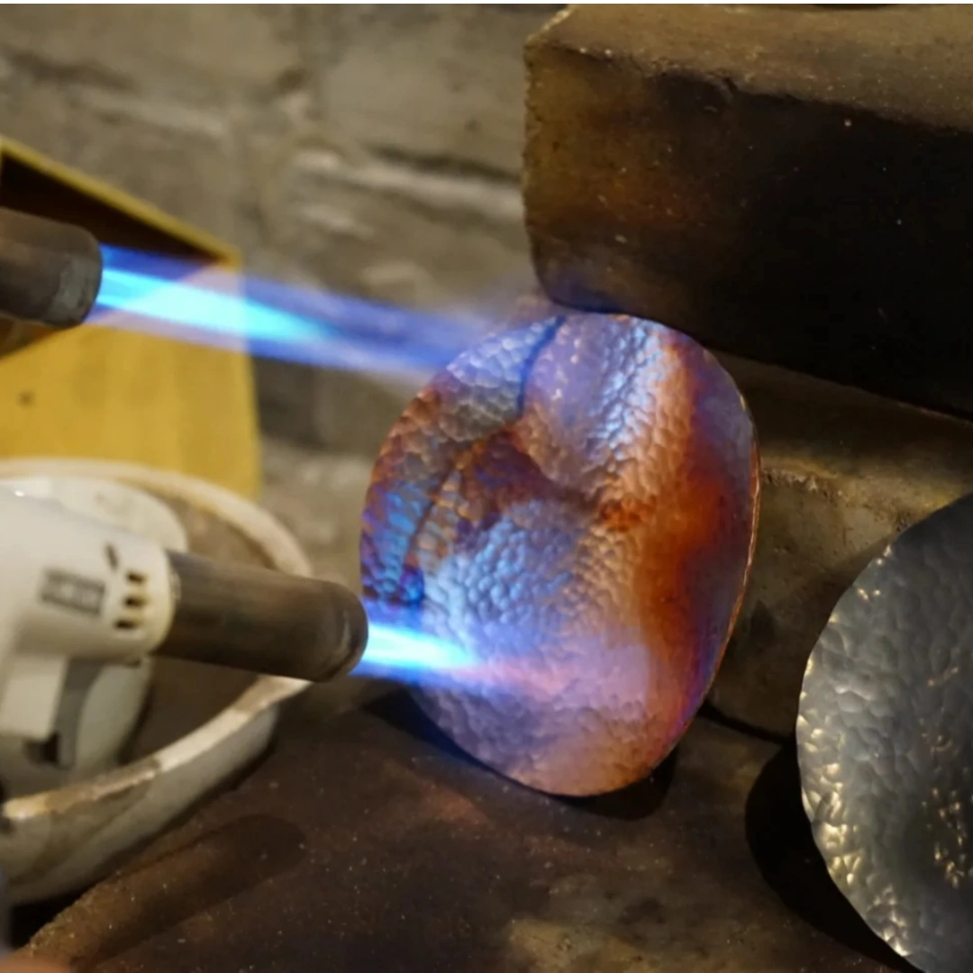 Detail of flame-oxidized copper surface showing rich patina and natural color variations from heat treatment, by Heritage & Craft.