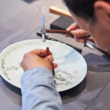 Detail of hand-carved ceramic artwork showing engraved texture and depth on celadon porcelain surface, by Heritage & Craft.